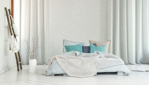 Een wit bed op de vloer met turquoise accessoires