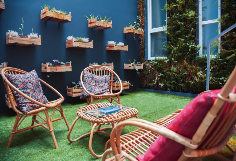 Een patio met blauwe muur en vertikale tuin